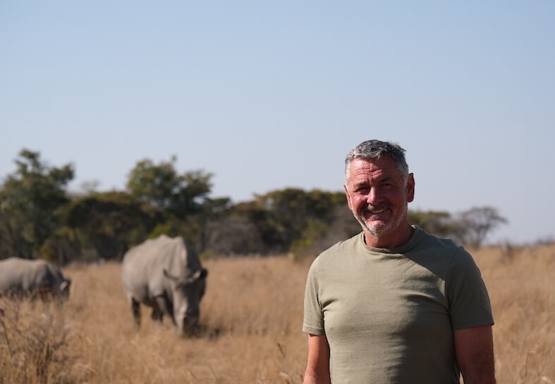 Volunteer standing in front of rhino in Zimbabwe