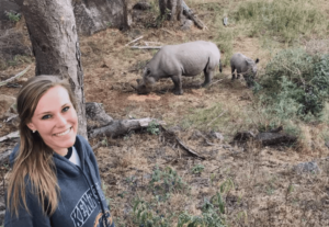 Volunteer with rhino and baby rhino in background