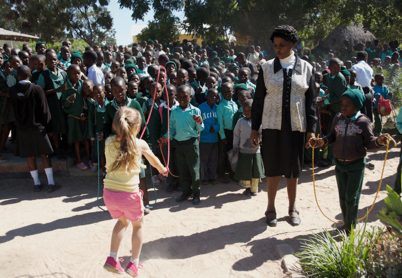 Girl skipping in front of class of African children
