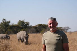 Mature volunteer with rhino in background