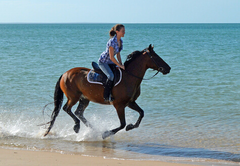 Girl galloping on the beach