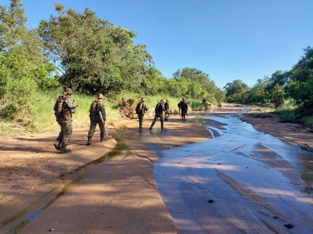 Anti-Poaching Rangers on patrol crossing a riverbed