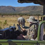 anti-poaching instructor watching rhinos from vehicle